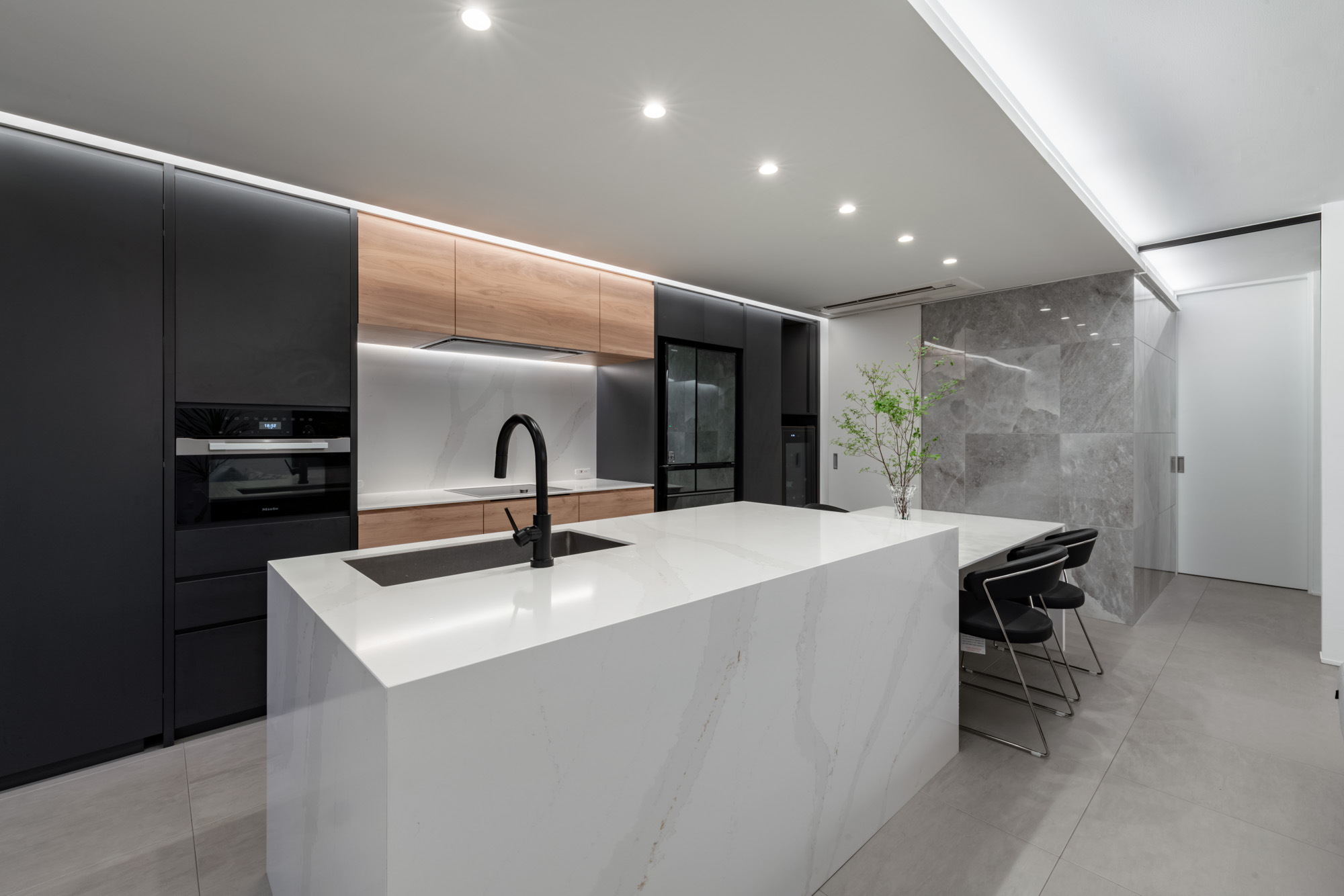キッチンとダイニングを照らすように天井に一直線にダウンライトが設けられた様子・デザイン住宅