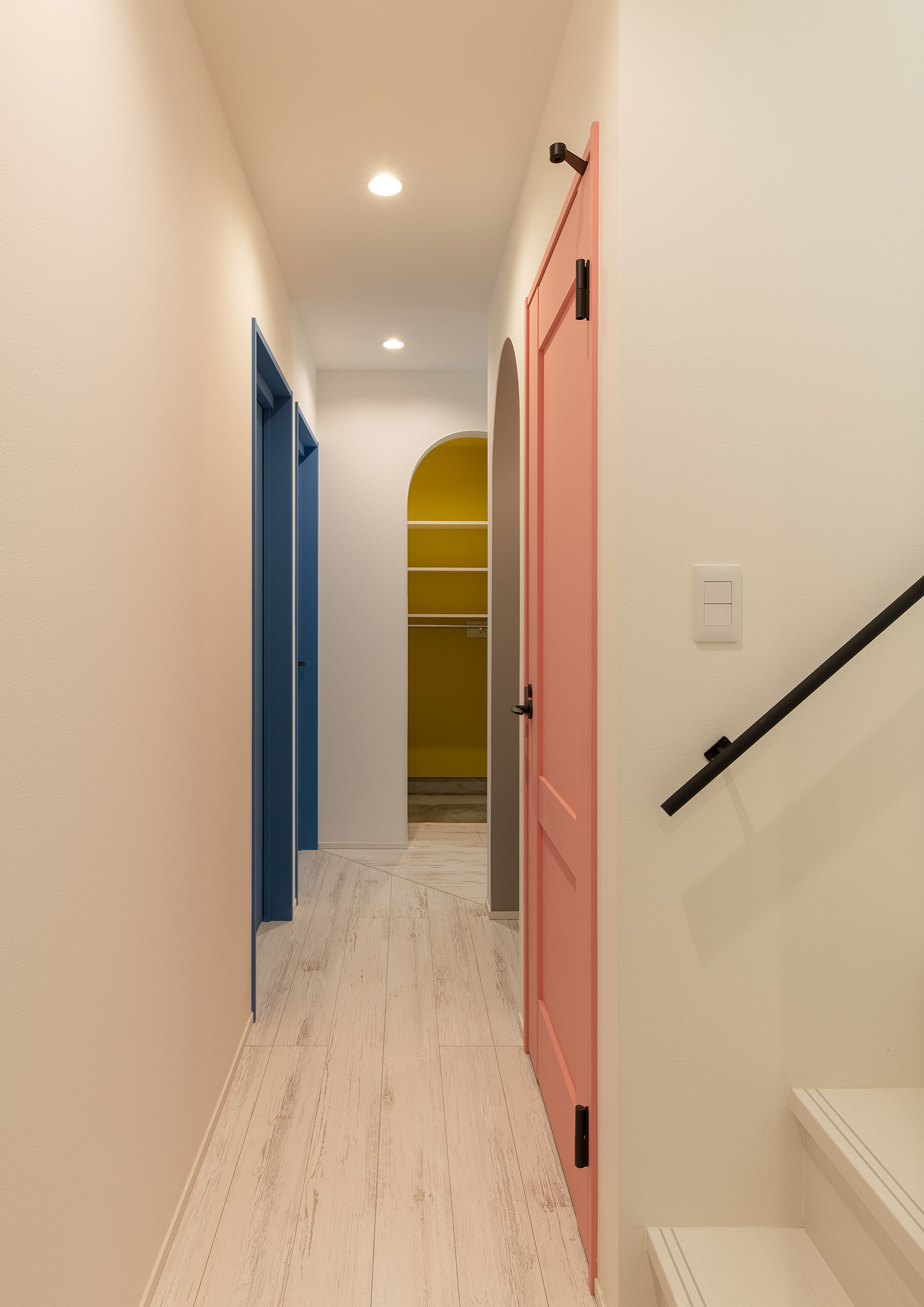 カラフルな壁紙や扉がある白を基調とした廊下・デザイン住宅