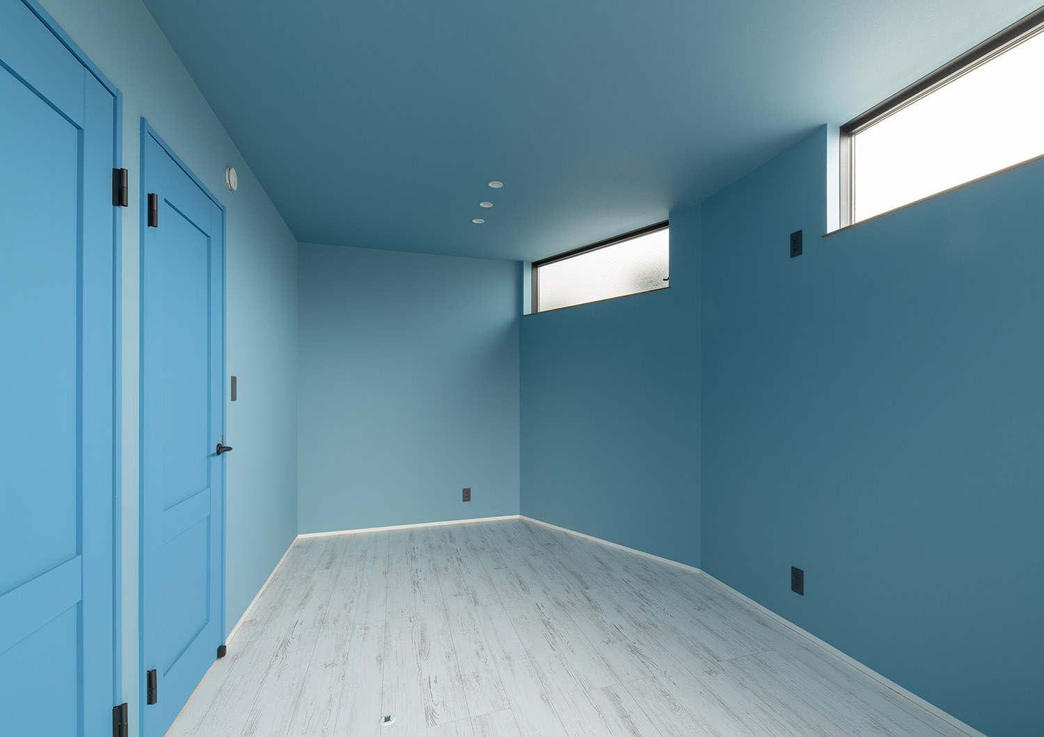 ハイサイドライトがある水色の扉と壁紙で左右対称の部屋・デザイン住宅