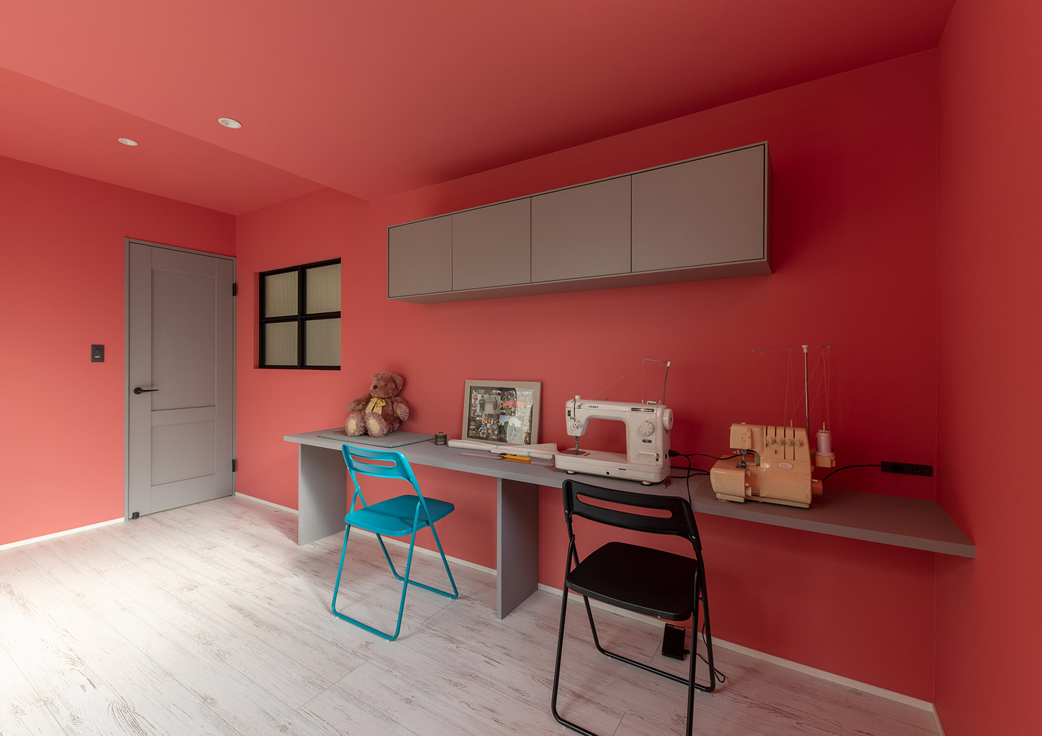 ピンク色の壁紙で壁付けデスクがある部屋・デザイン住宅