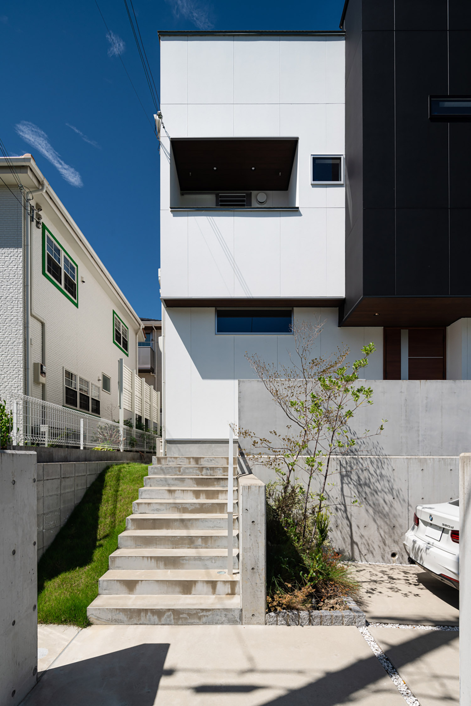 コンクリートの階段アプローチがある白と黒の外壁の住宅・デザイン住宅