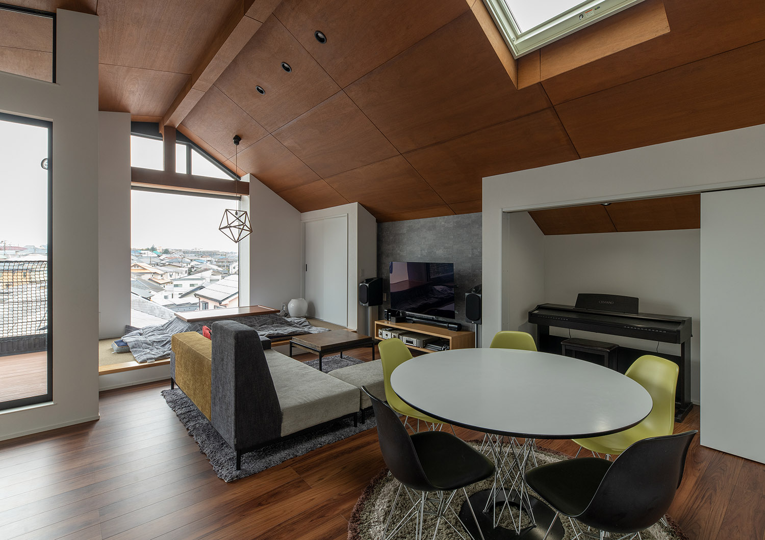 丸いテーブルやピアノが置かれた木の高天井のLDK・デザイン住宅
