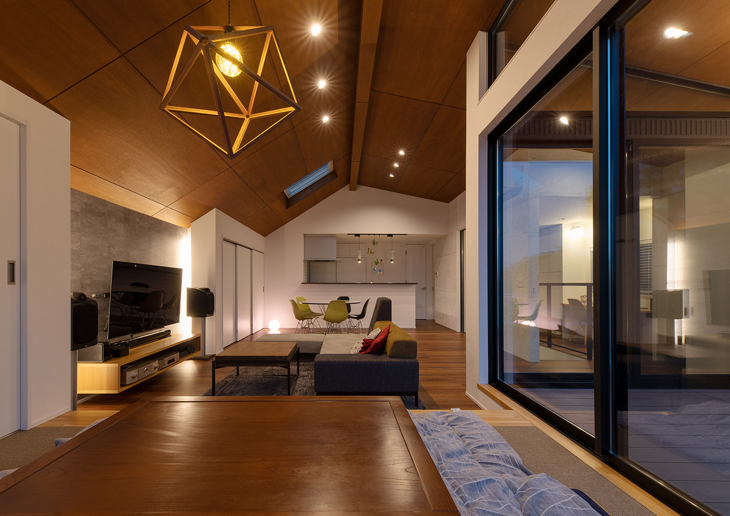 天井にダウンライトと木のペンダントライトが取り付けられた、バルコニーと繋がるLDK・デザイン住宅