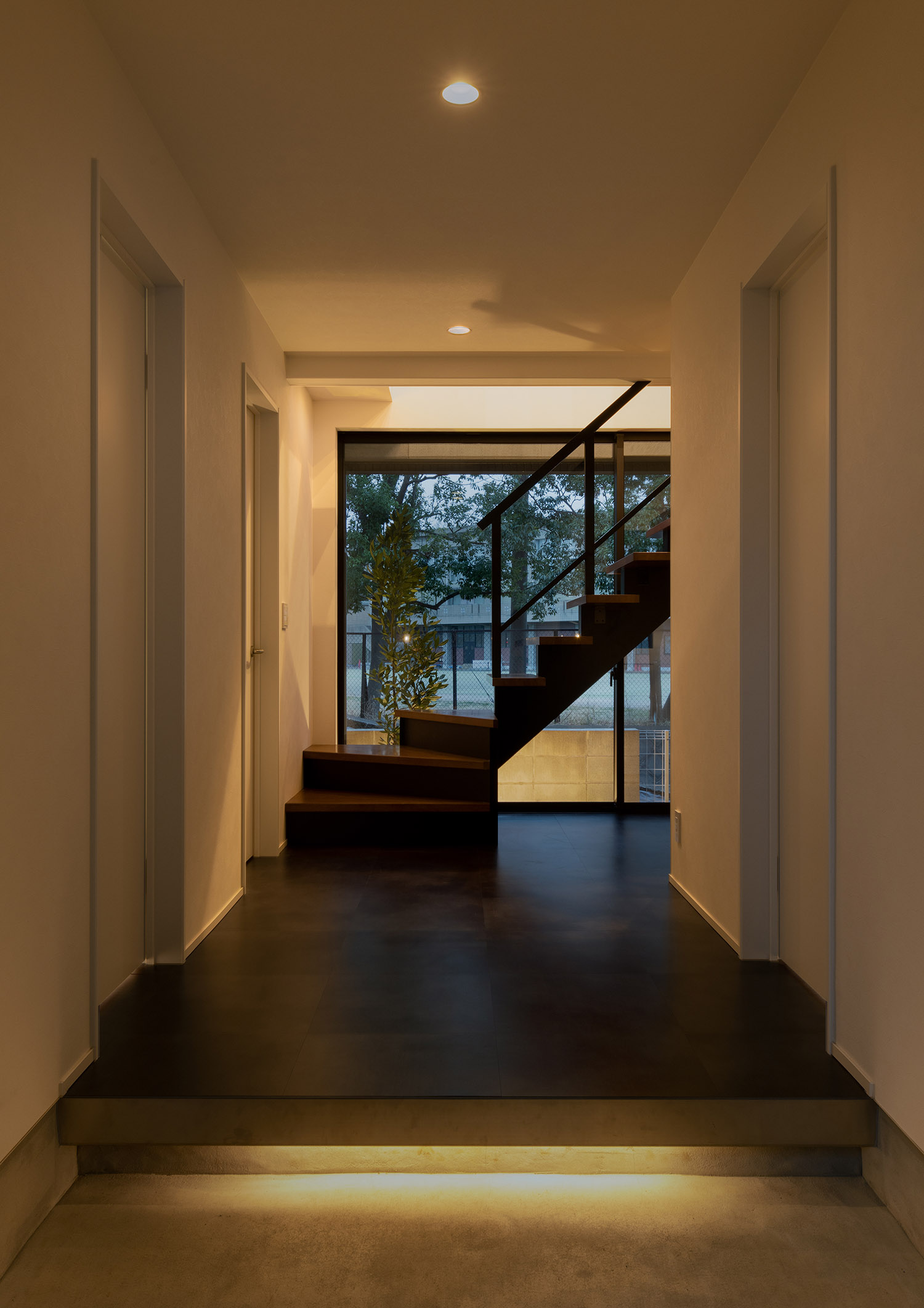 足元に間接照明が取り付けられ、正面にスケルトン階段がある玄関・デザイン住宅