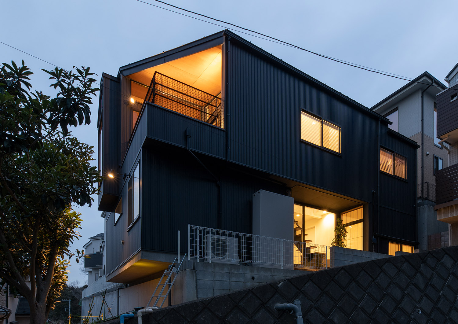 バルコニーから光が漏れる、高台に建つ黒い外壁の住宅・デザイン住宅