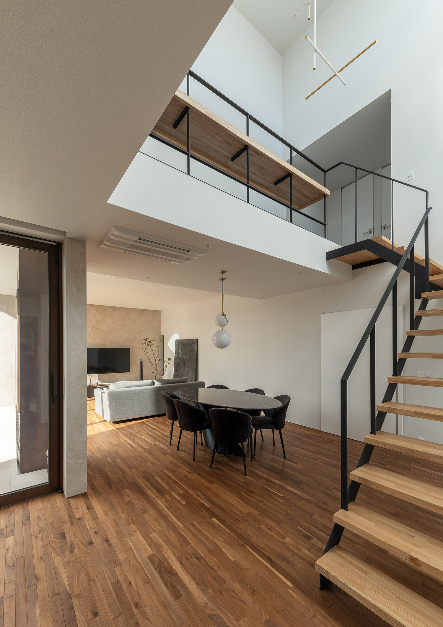 木製のリビングイン階段の手すりが吹き抜けまで伸びている様子・デザイン住宅