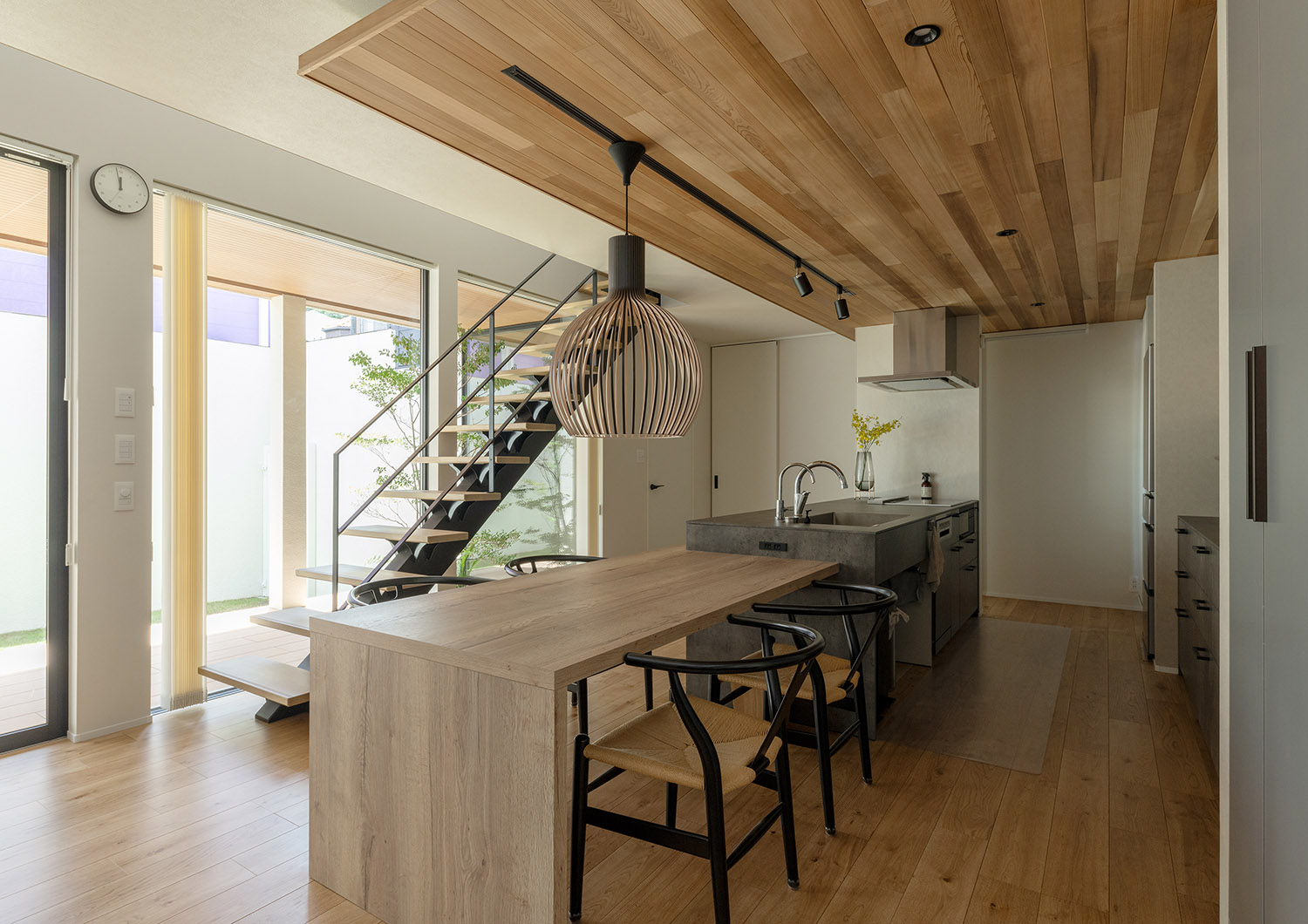 ペニンシュラキッチンと木のダイニングテーブルが横並びになっている様子・デザイン住宅