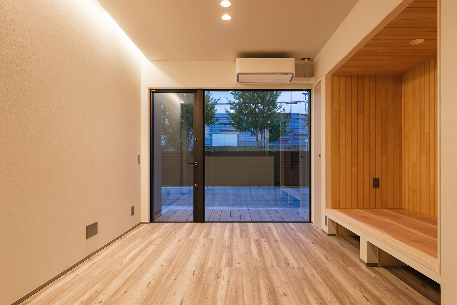 壁際の間接照明と天井のダウンライトに照らされるLDK・デザイン住宅