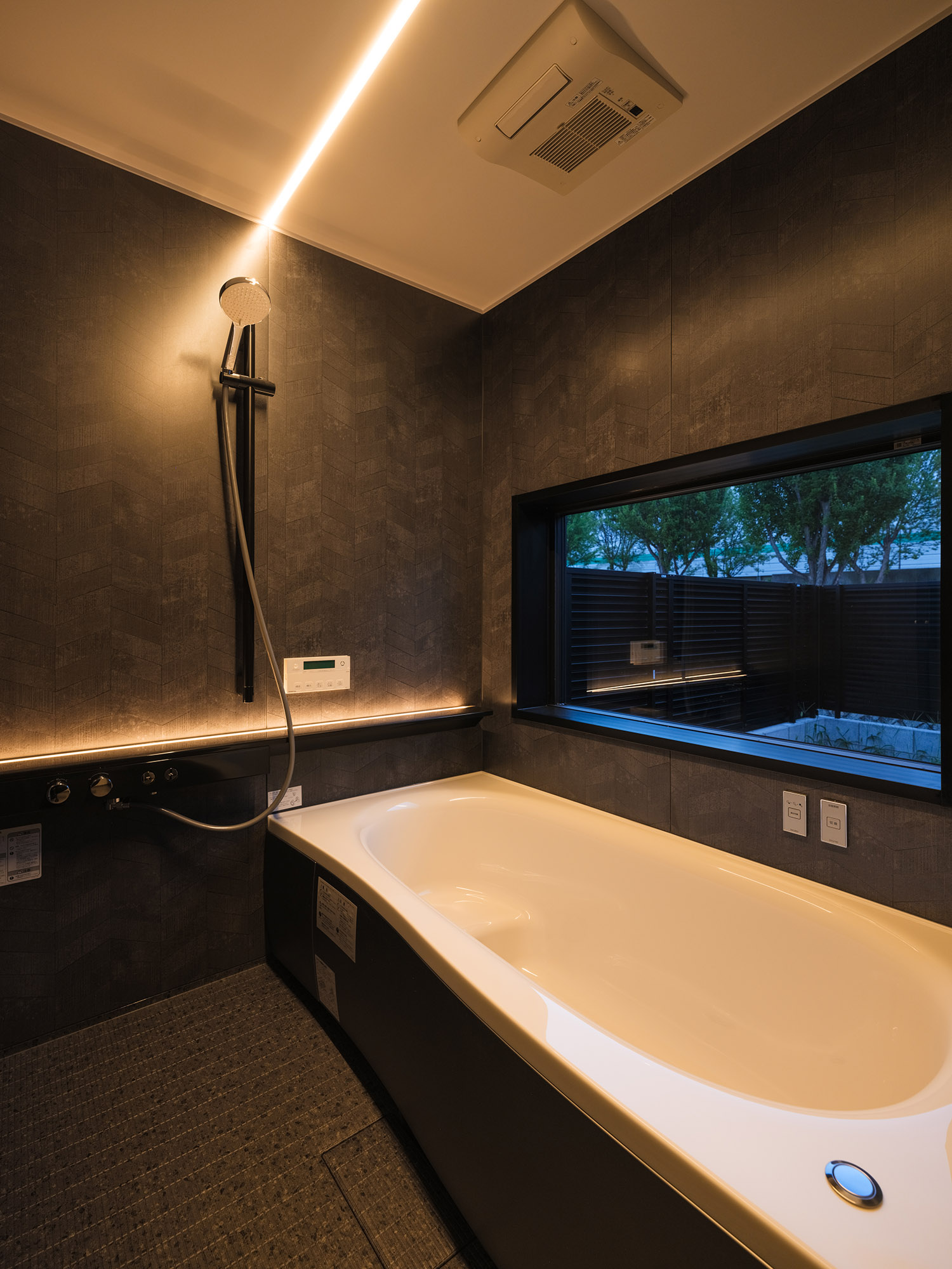線状の照明が取り付けられた、窓のある黒い壁の浴室・デザイン住宅