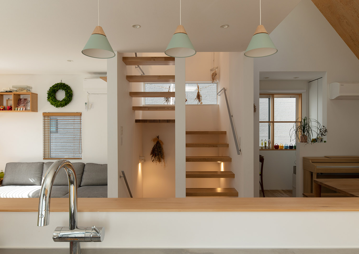 キッチンの正面に木のスケルトン階段が見えるナチュラルな空間・デザイン住宅