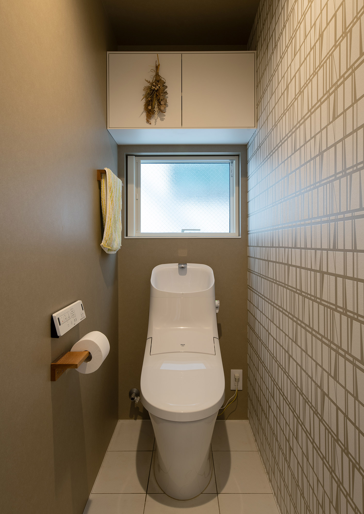 曇りガラスの窓から光が入る、アクセントクロスを設けた明るいトイレ・デザイン住宅