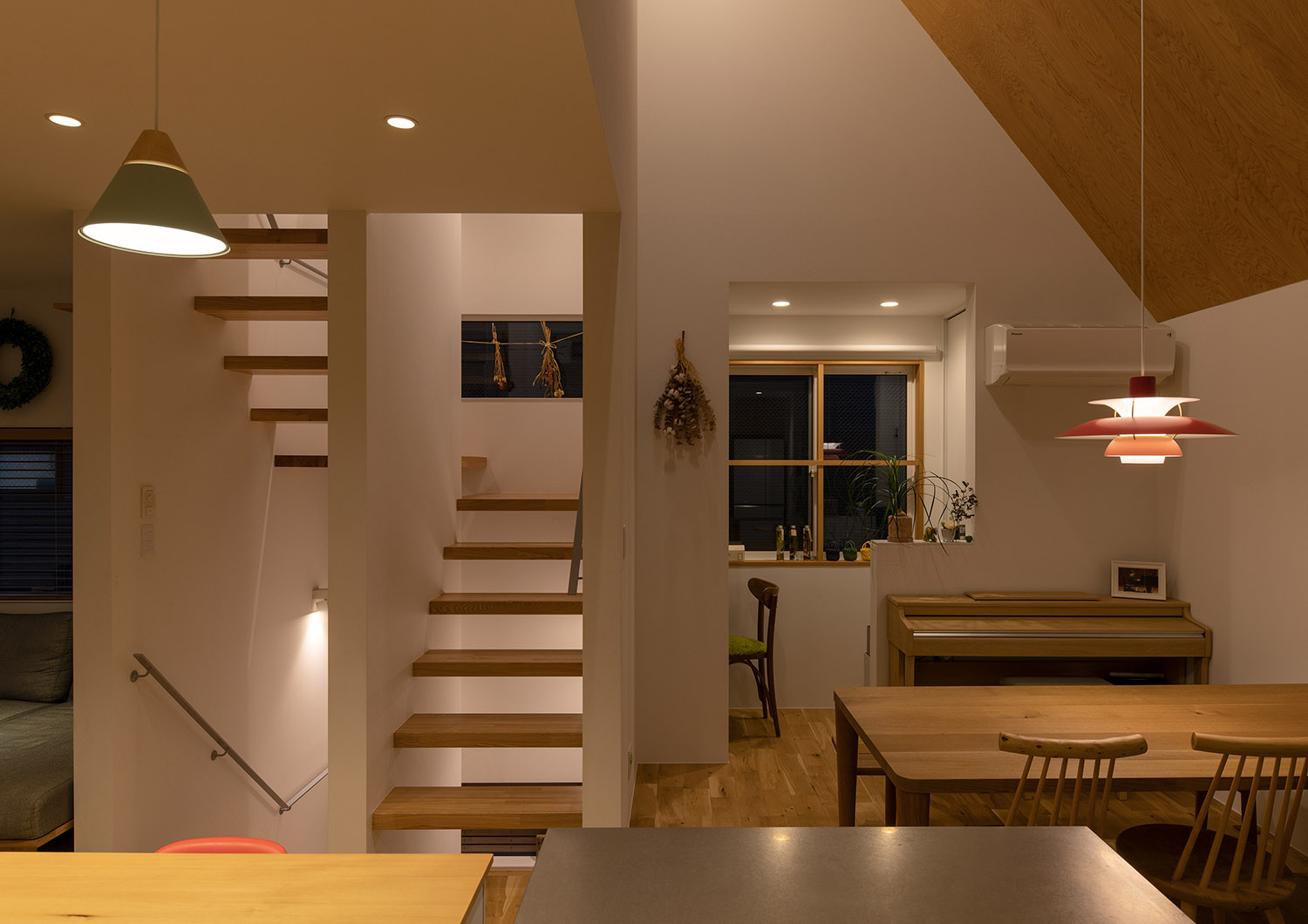 木のインテリアでまとめられた、おしゃれなペンダントライトに照らされるLDK・デザイン住宅