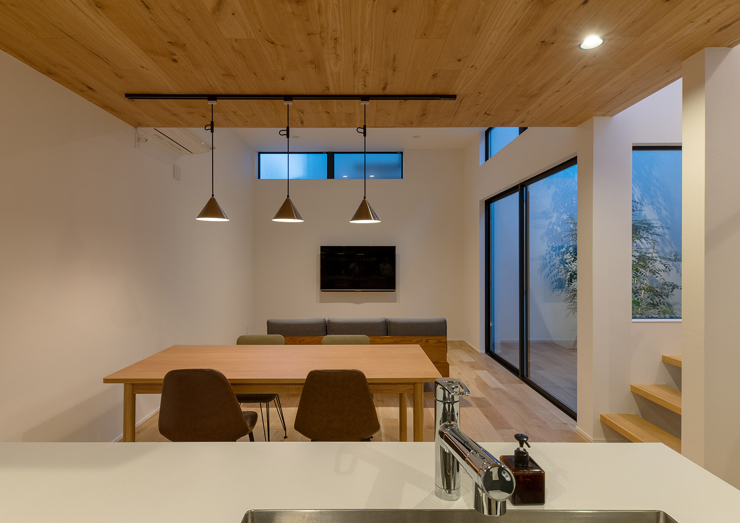 木のダイニングテーブルがペンダントライトに照らされるナチュラルなLDK・デザイン住宅