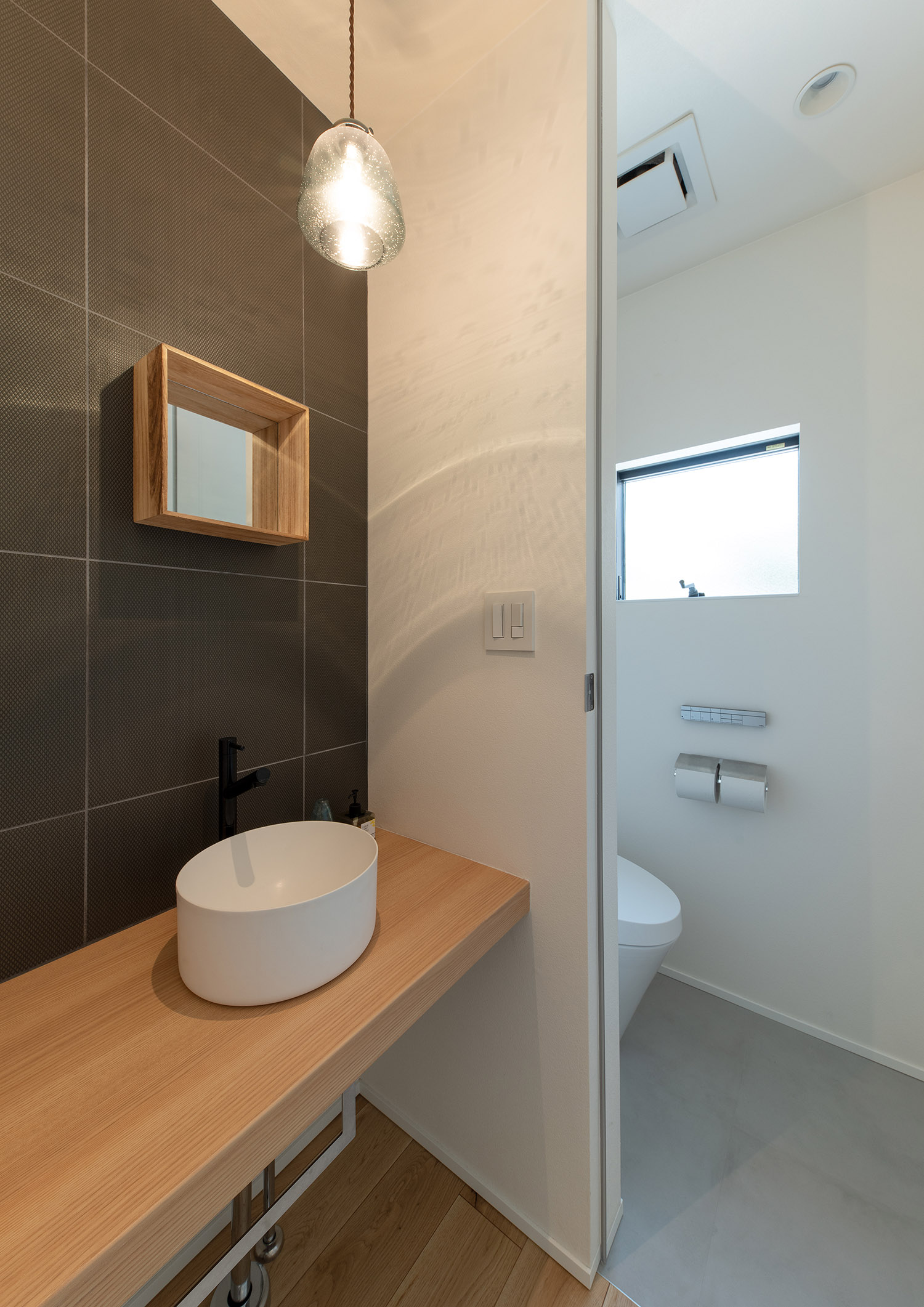 おしゃれな手洗いカウンターとトイレが扉で仕切られたデザイン・デザイン住宅