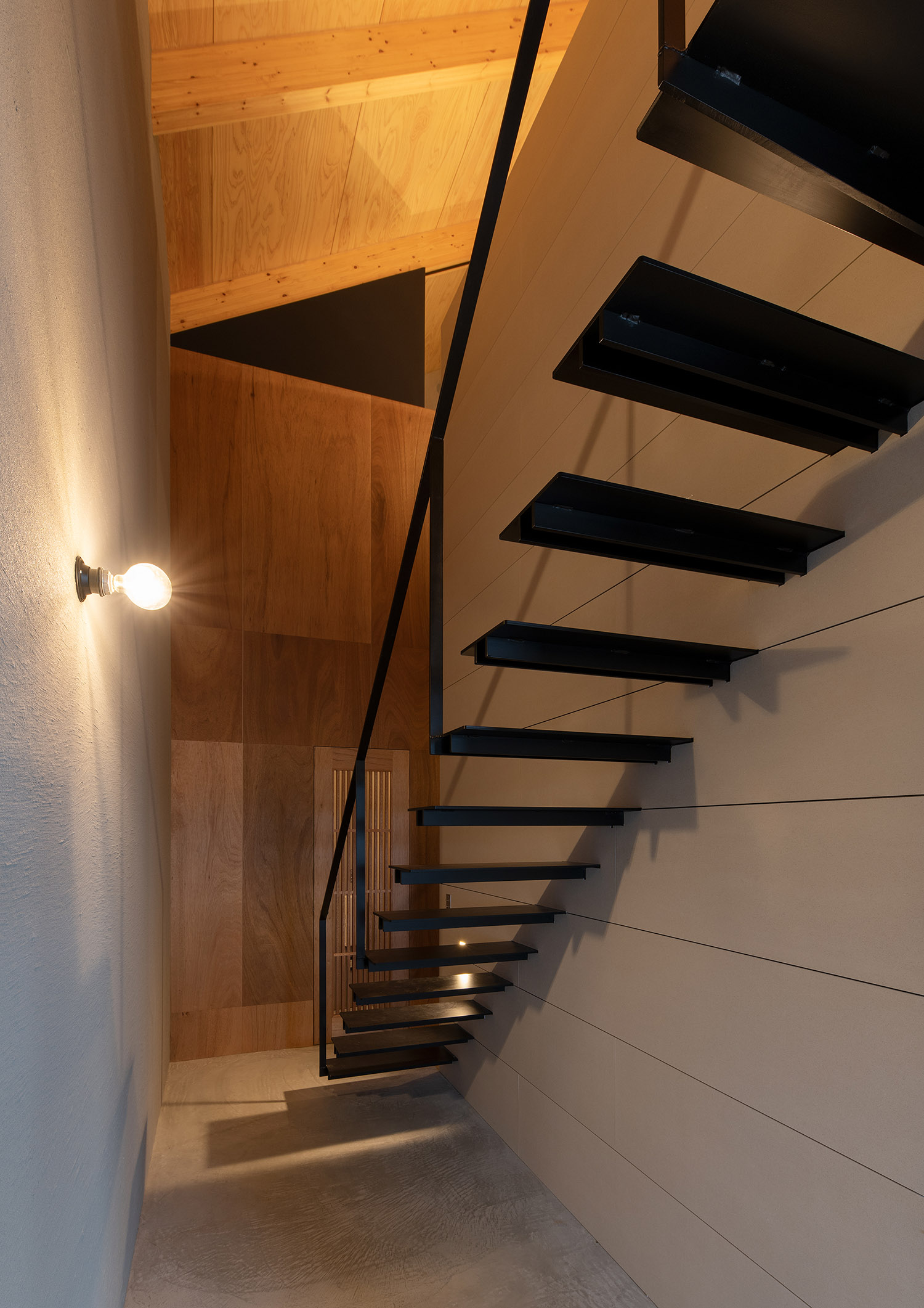 壁に間接照明が取り付けられた土間空間にあるスケルトン階段・デザイン住宅