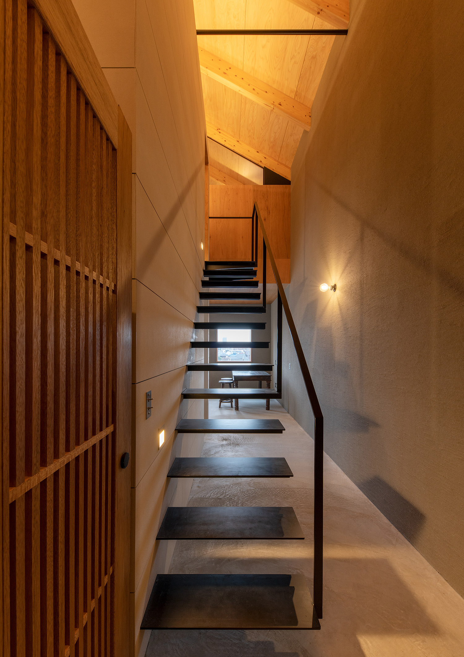 木の壁の吹き抜けの空間にある浮いたデザインのスケルトン階段・デザイン住宅