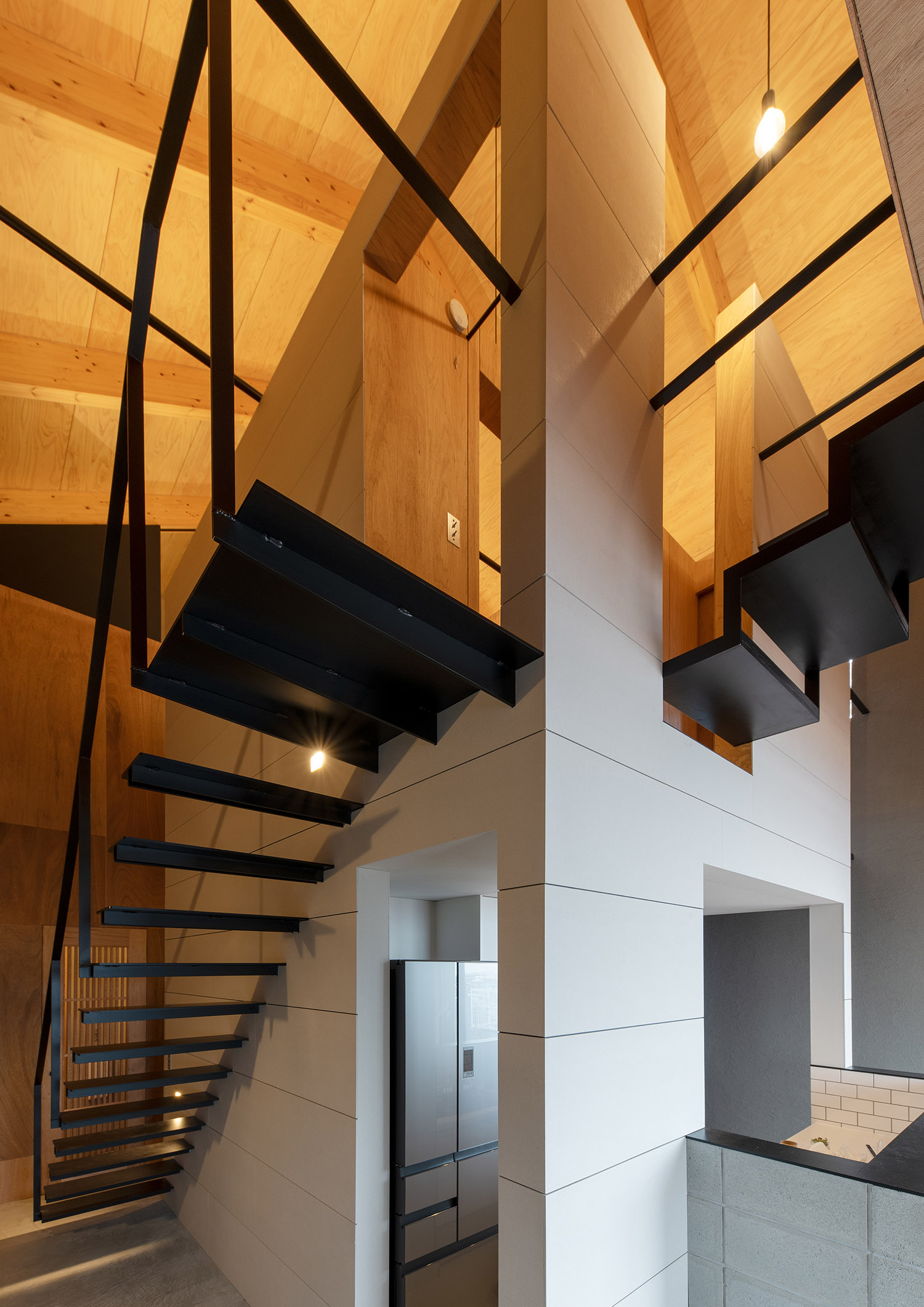 吹き抜け空間にある黒いシャープなスケルトン階段・デザイン住宅