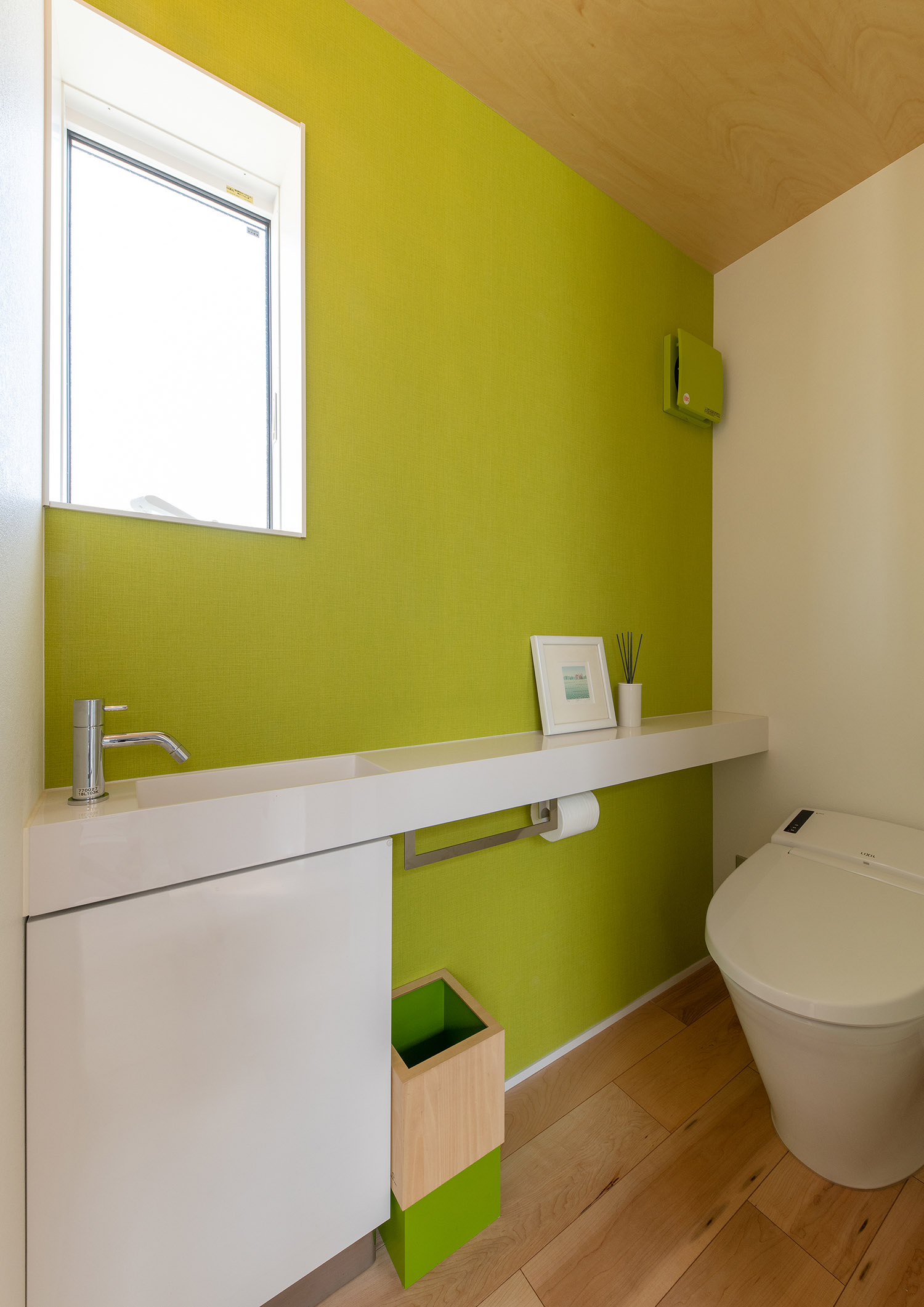 グリーンのアクセントクロスがある薄型手洗い付きのトイレ・デザイン住宅
