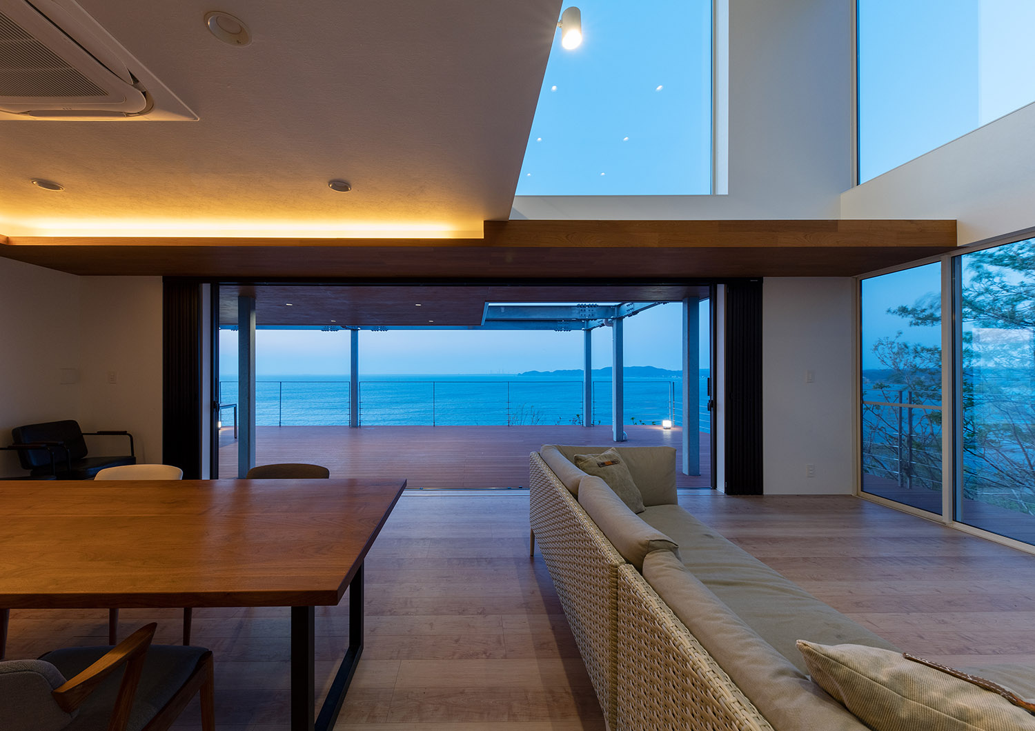 天井に間接照明を取り付けた、窓から海が見える高級感のあるLDK・デザイン住宅