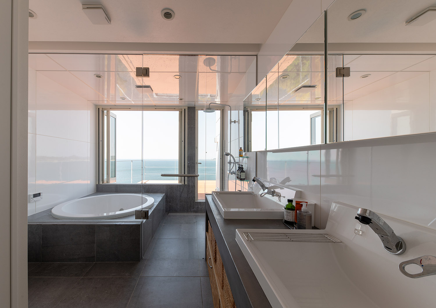 洗面所と浴室がガラスで仕切られた海の見える開放的な浴室・デザイン住宅