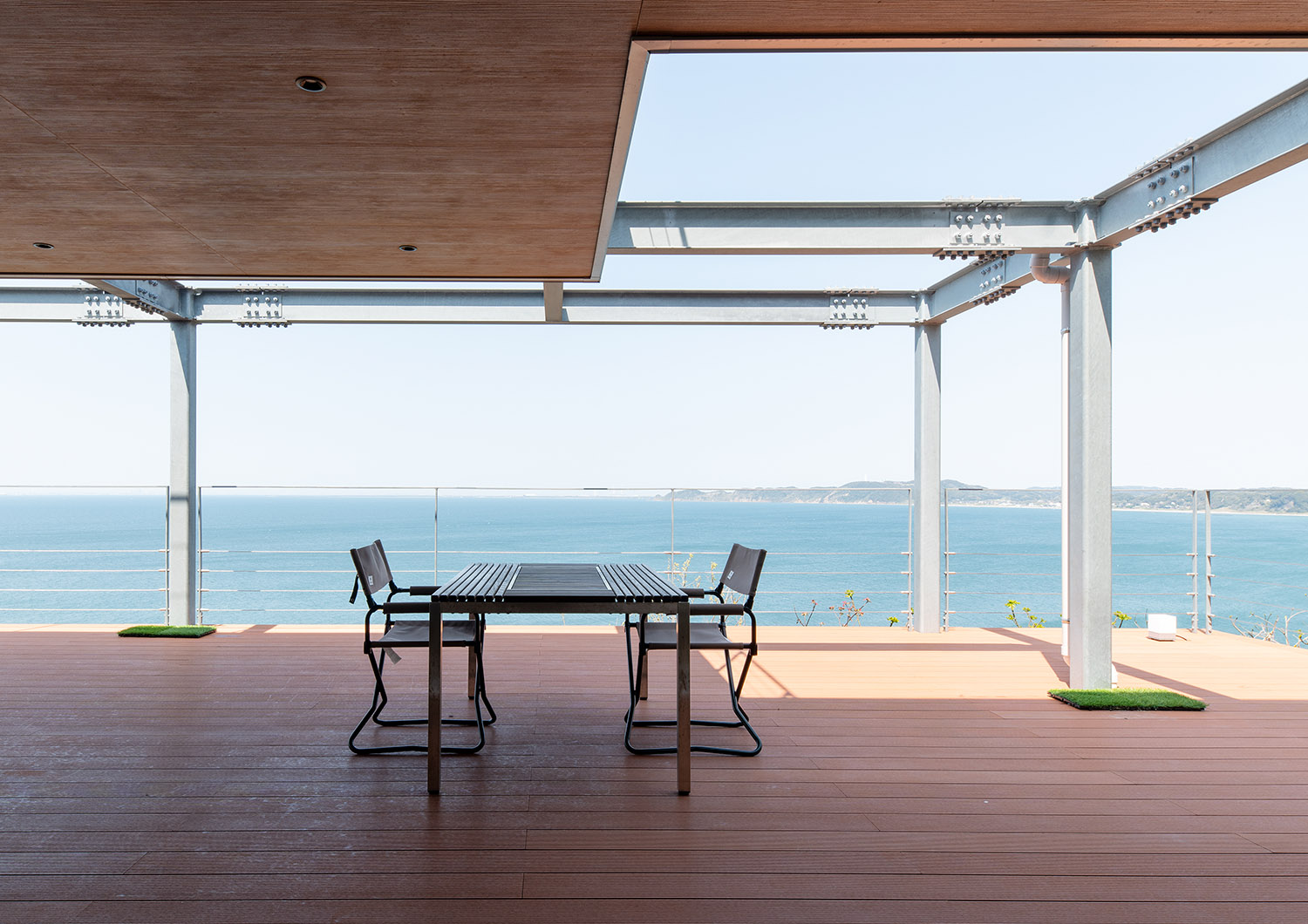 海に面した木目の軒天井のあるウッドデッキのテラス・デザイン住宅