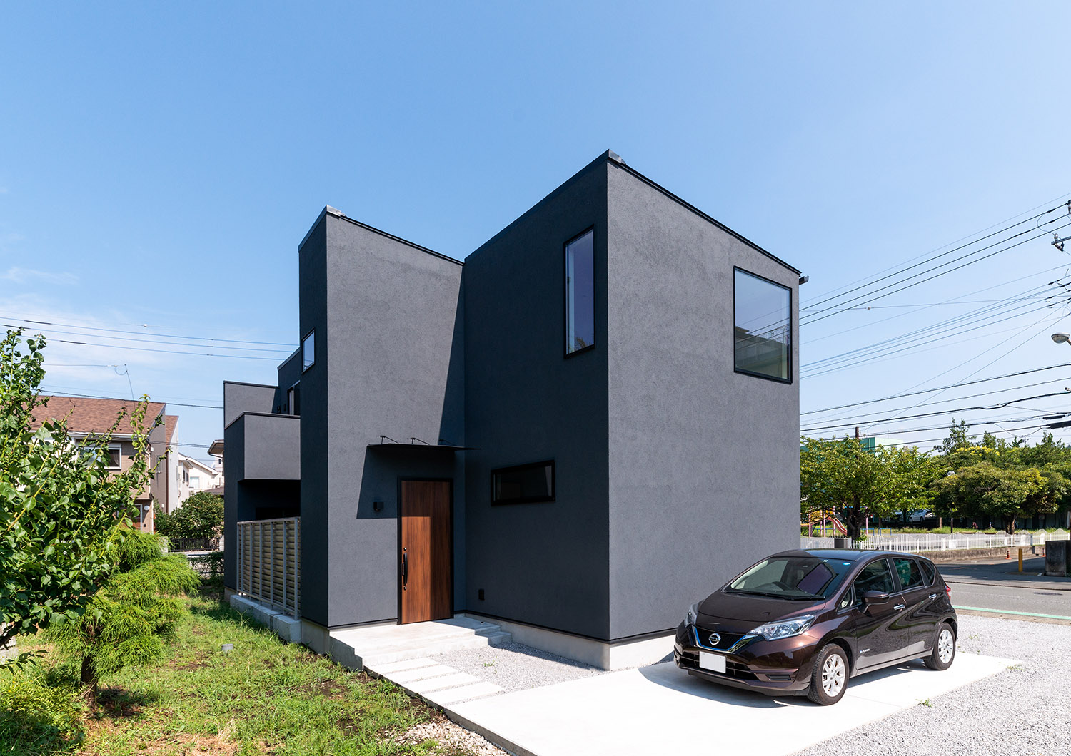 黒い外壁の家の前に車が一台止められている様子・デザイン住宅