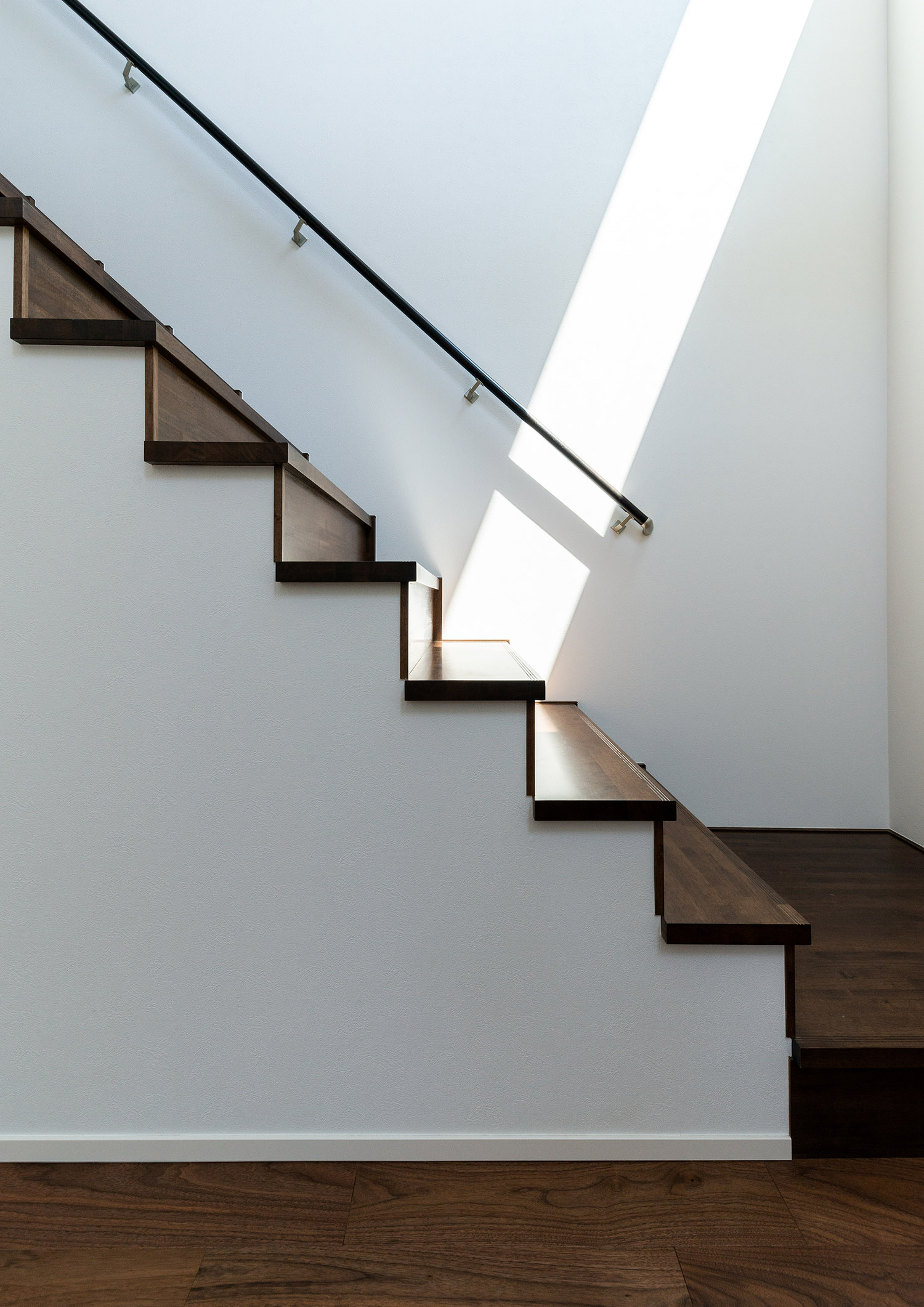 フローリングや壁と馴染むような白と木材の箱型階段・デザイン住宅