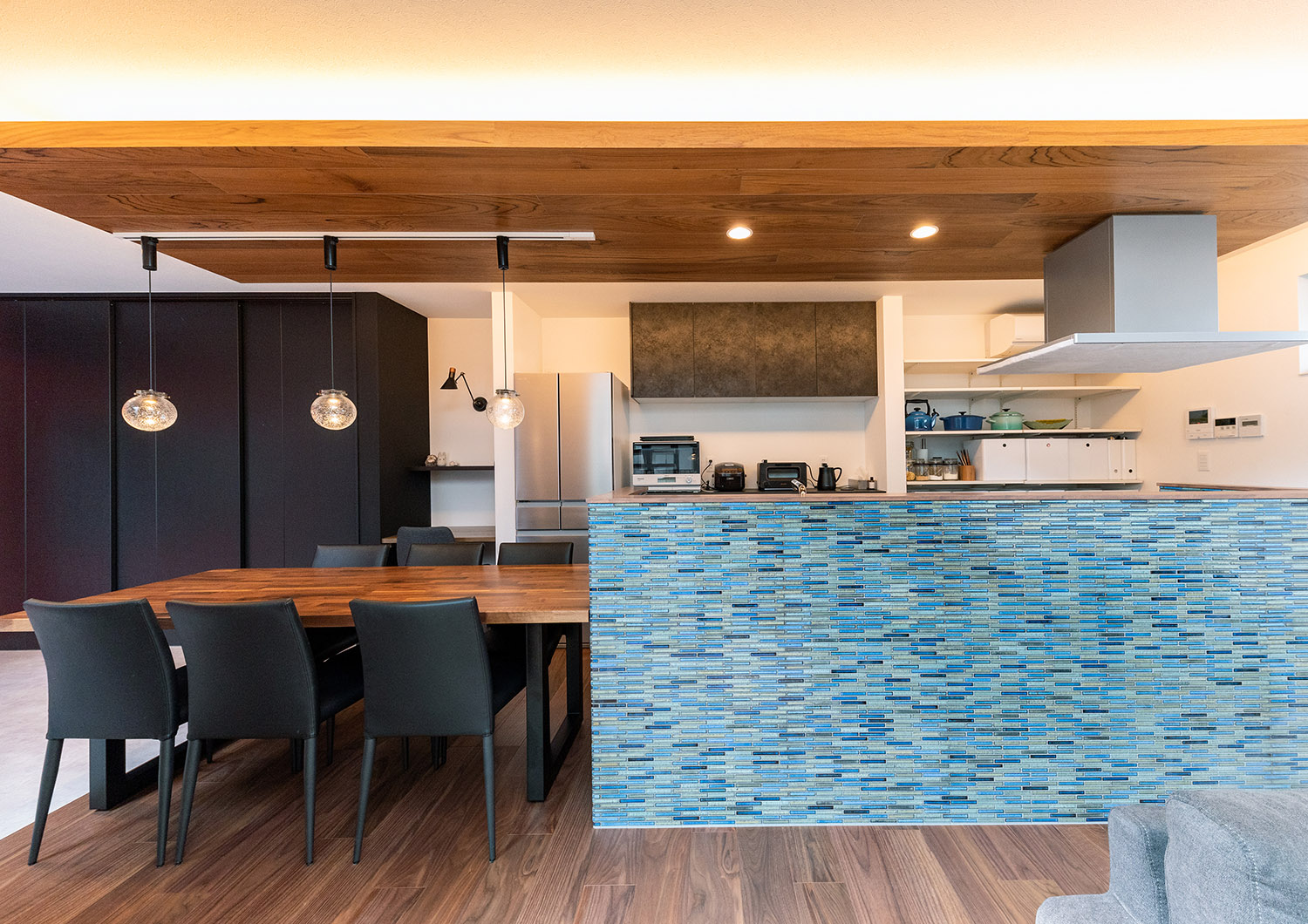 ダイニングテーブルが一体となった青いタイルの腰壁付きキッチン・デザイン住宅