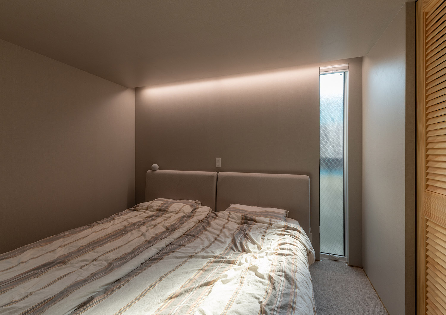 壁際に間接照明を取り付けたスリット窓のあるおしゃれな寝室・デザイン住宅