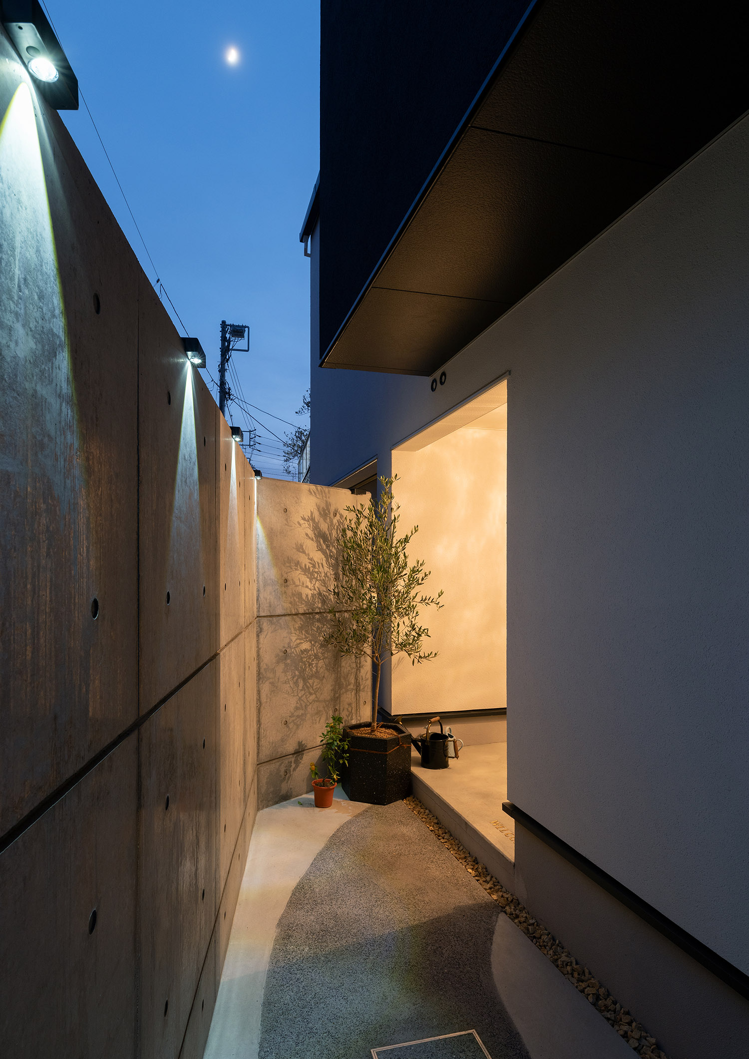 コンクリートの高い目隠し壁を取り付けたプライバシー性の高いアプローチ・デザイン住宅