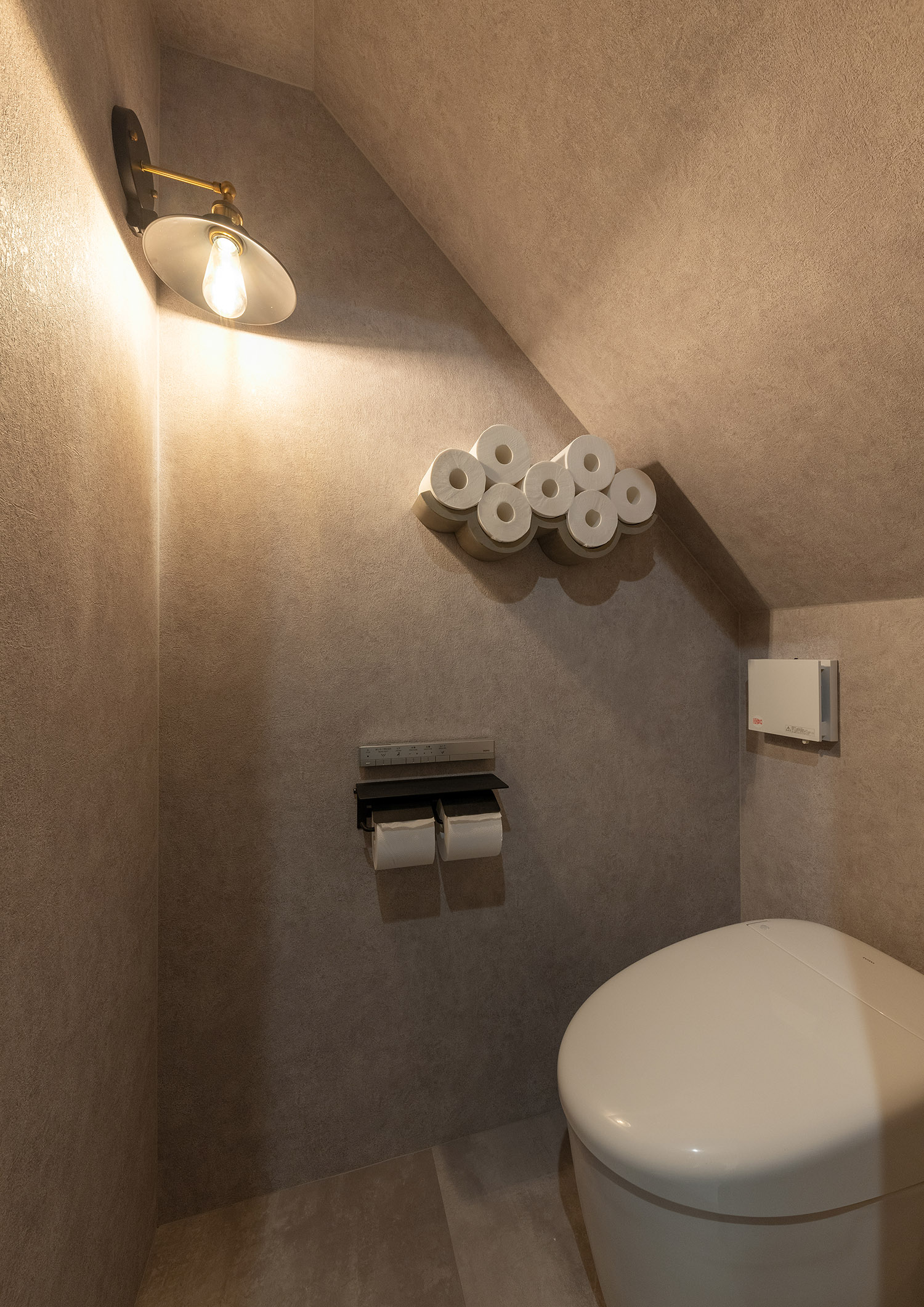 トイレットペーパー専用のおしゃれな収納や間接照明を取り付けた母屋下がりのトイレ・デザイン住宅
